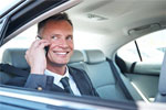 A distinguished businessman sitting in the back seat of a premium taxi, smiling while engaged in a phone conversation.