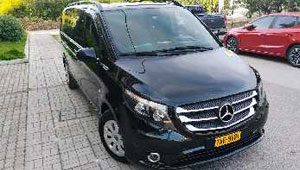 A glossy black Mercedes Vito minivan parked under the bright sun, showcasing its spacious and modern design.